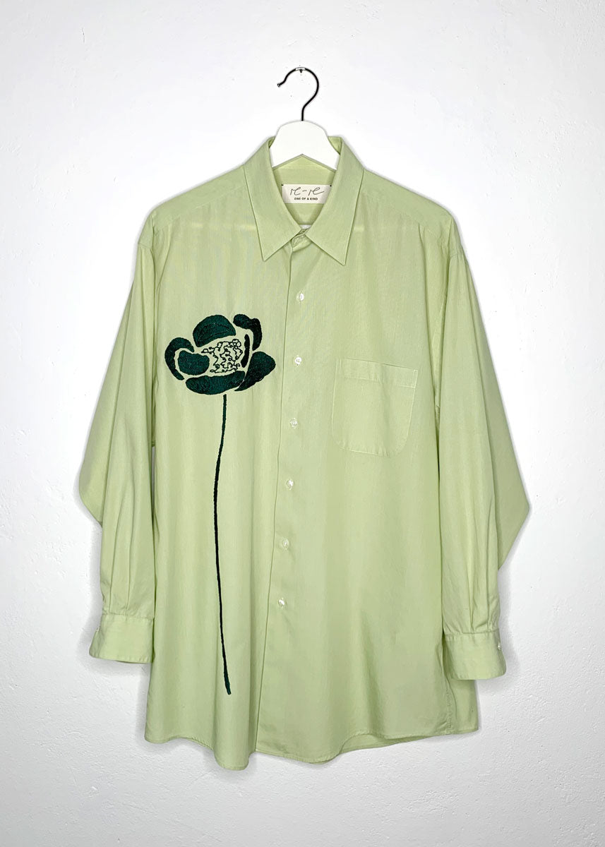 Green shirt with hand embroidered green flower at front.