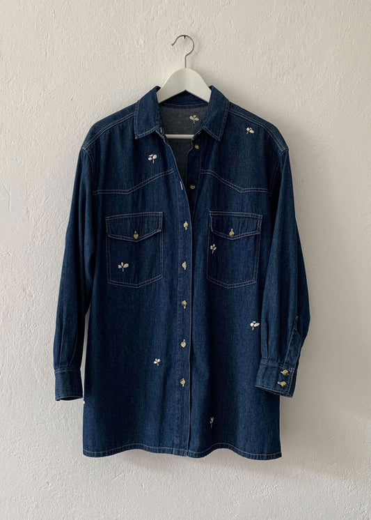 denim shirt with small hand embroidered flowers hanging on hanger