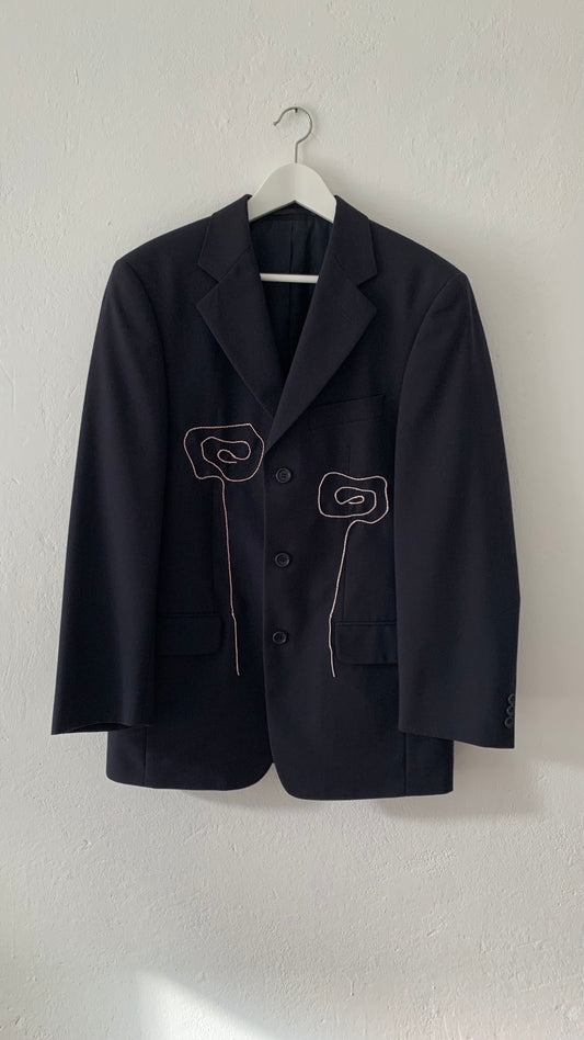 Navy blazer on hanger with hand embroidered flowers at front.