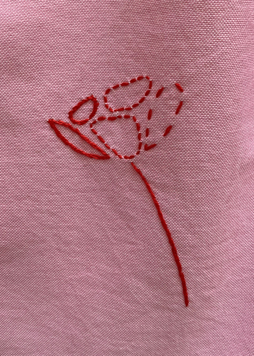 Hand embroidered red flower on pink cotton.